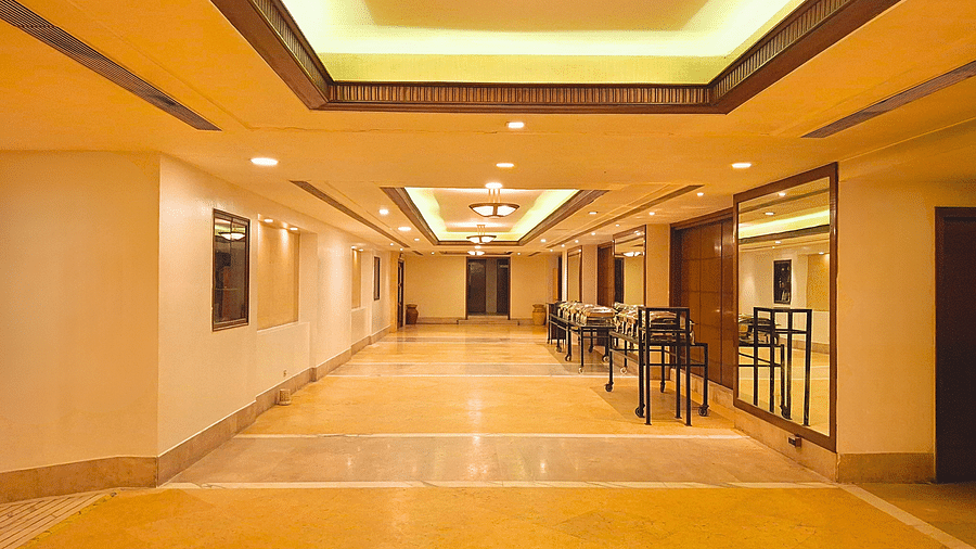 A well-lit corridor at Pride Plaza Ahmedabad, featuring a marble floor, warm lighting, and elegant decor.